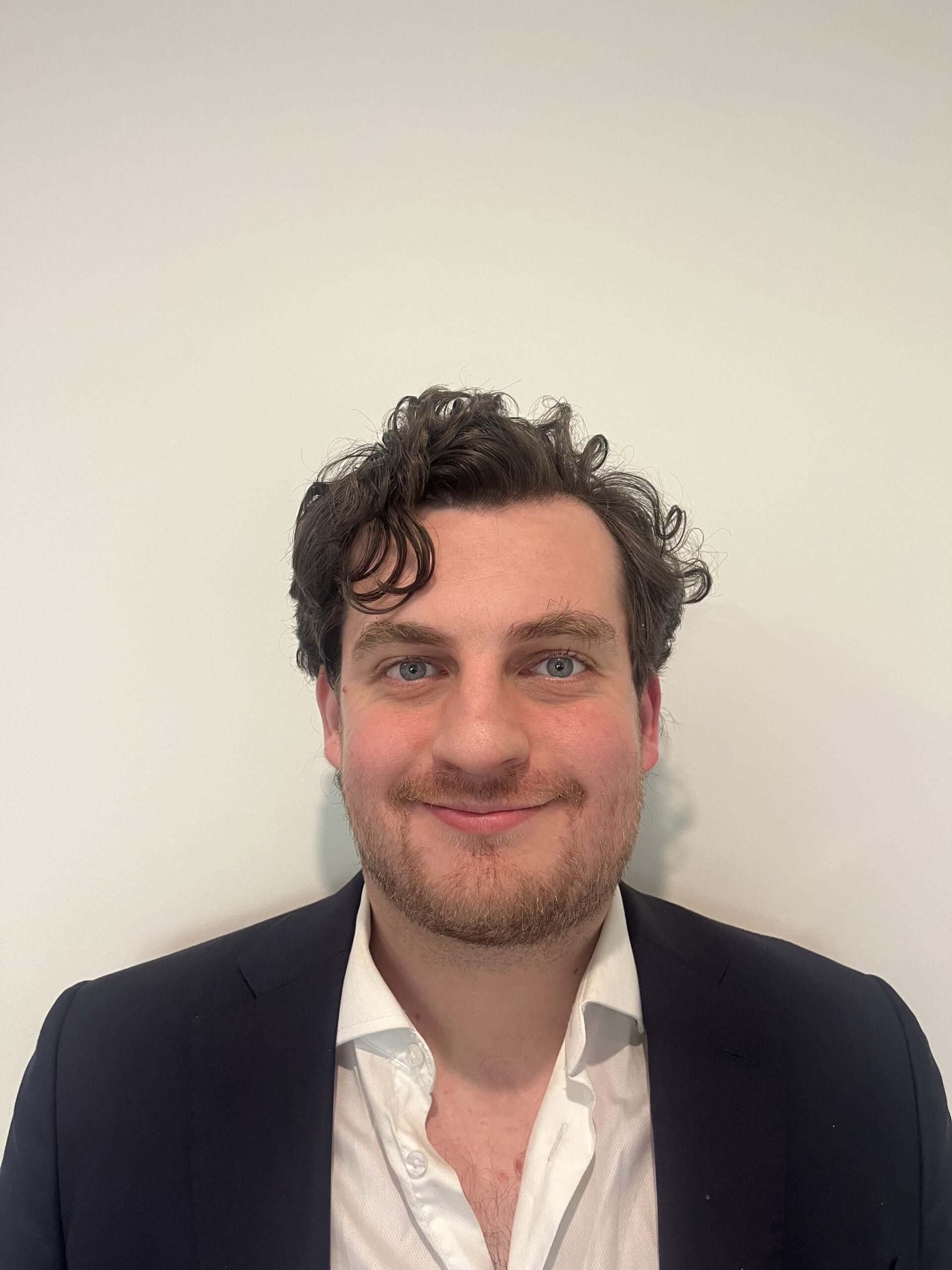 man in front of neutral background wearing blazer