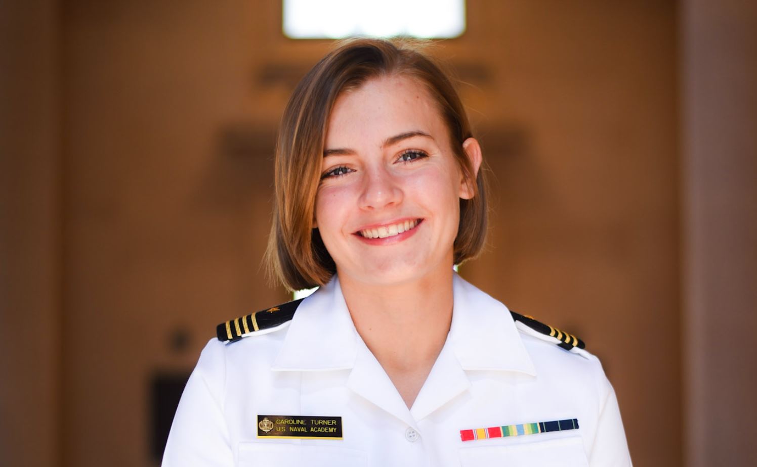 Caroline Turner in white naval uniform with blurred background.